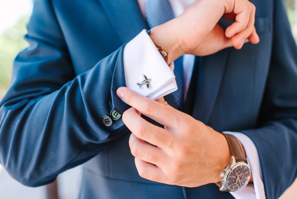 Hispanic groom adjusting his plane cufflinks and suit sleeves